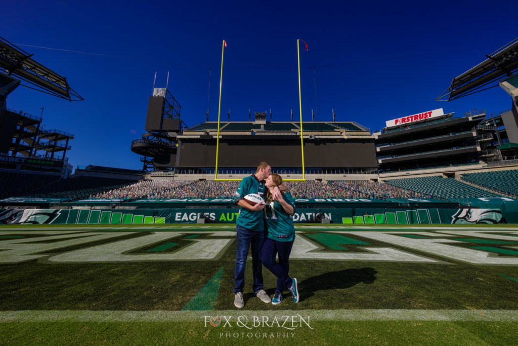 Two adults kiss standing on football field