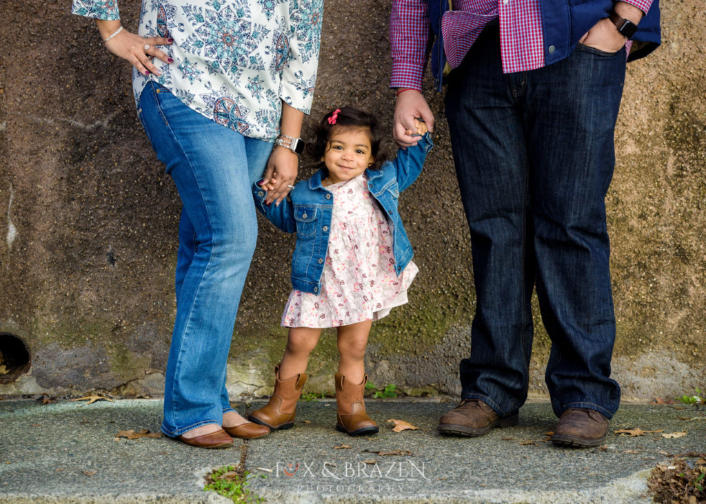 Toddler girl standing with parents