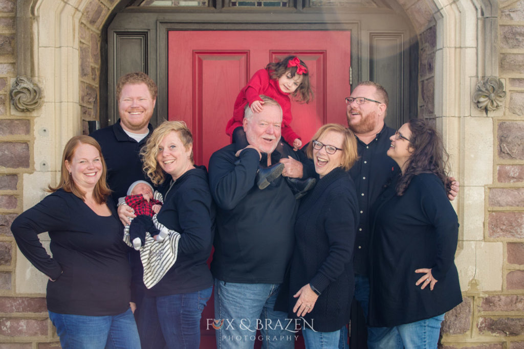 Multi-generation photo of family dressed in black in front of red door