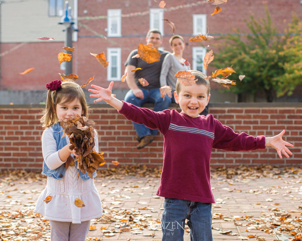 Two kids throw leaves in the air