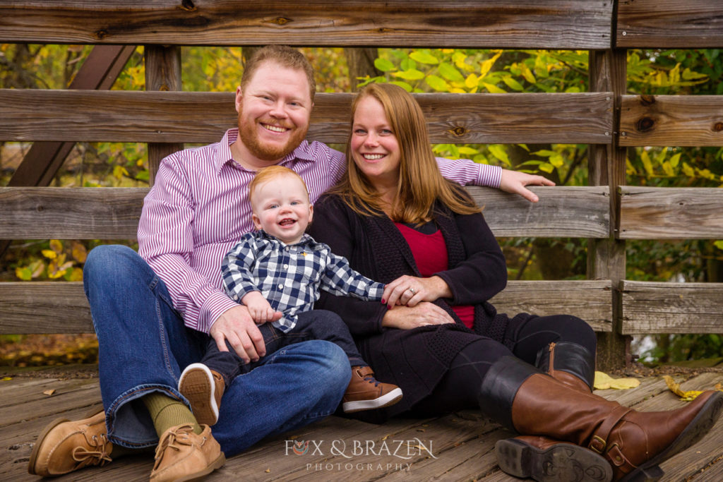 Mom and Dad snuggle one year old at mini sessions in Phoenixville