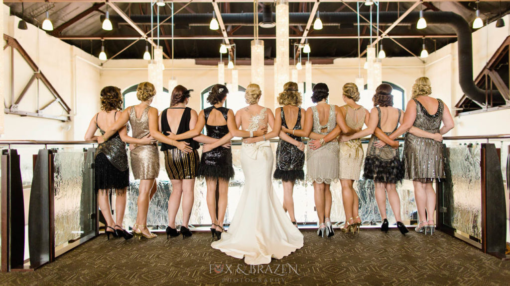 Ten women stand showing off backs of elegant gowns
