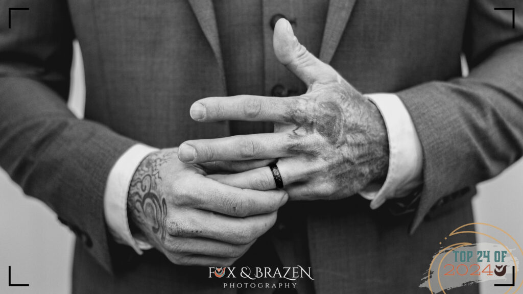 Close-up of groom's ring and hands.