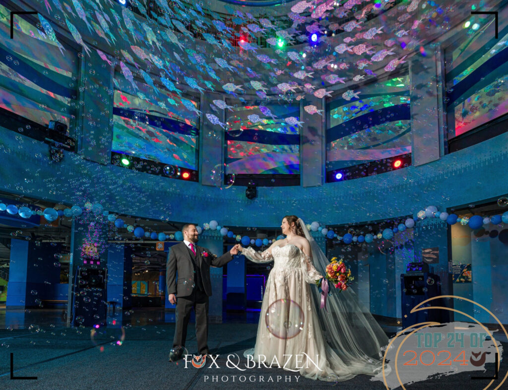 Newlywed couple surrounded by bubbles in Adventure Aquarium rotunda.