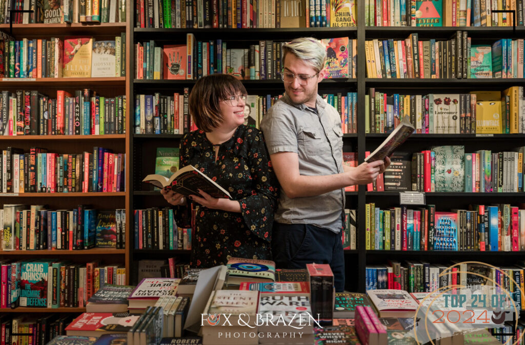 Engaged couple laughing together at a bookstore in Phoenixville surrounded by 2024 book titles.