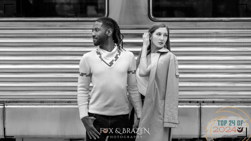 Engaged couple posing near a vintage train car for Shutterfest 2024.
