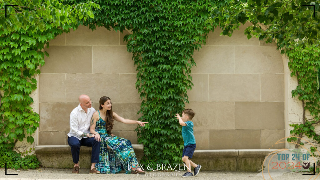 Child striking a dinosaur pose in garden scenery at Longwood Gardens 2024 with his parents