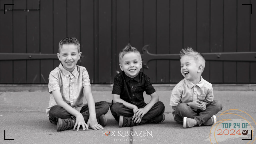 Three siblings laughing together in a family photo.