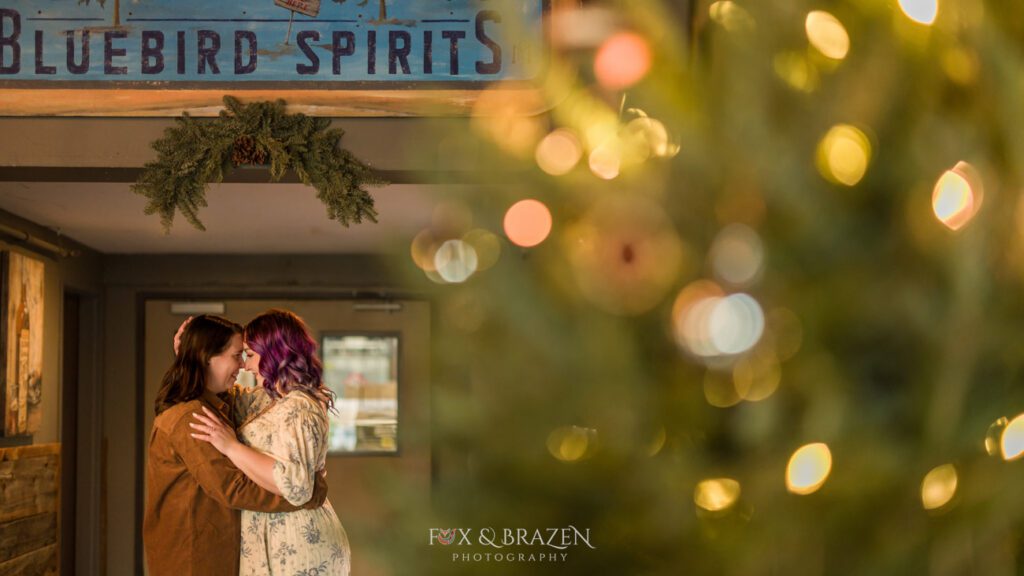 Kelly and Margaret inside Bluebird Distilling with holiday lights in the foreground.