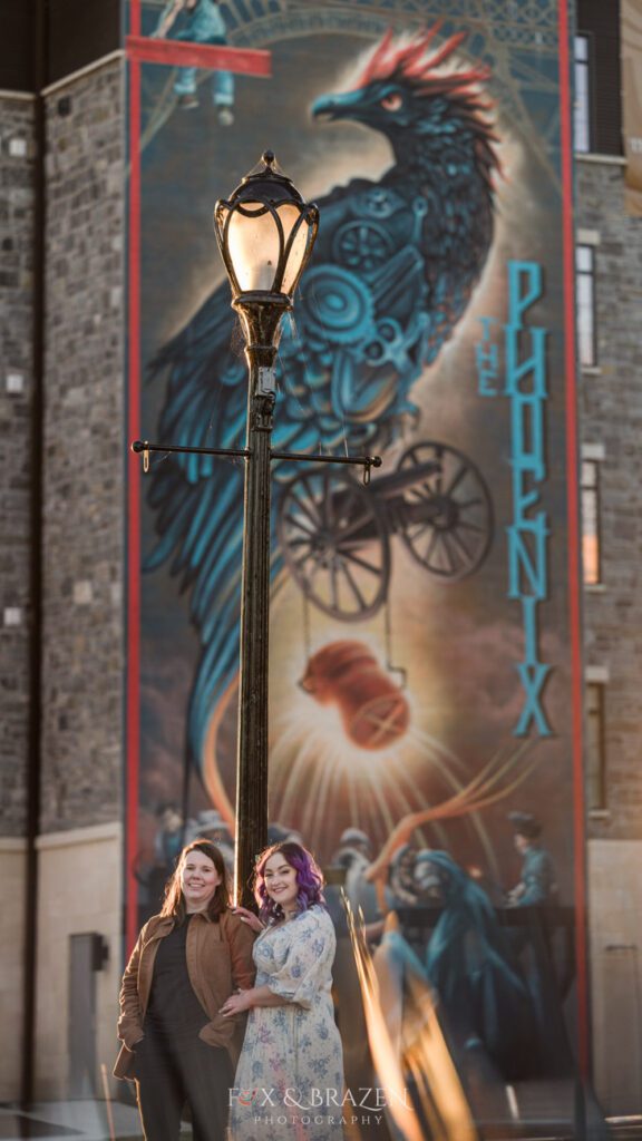 Engaged couple smiling under the phoenix mural in Phoenixville for their Downtown Phoenixville engagement adventure