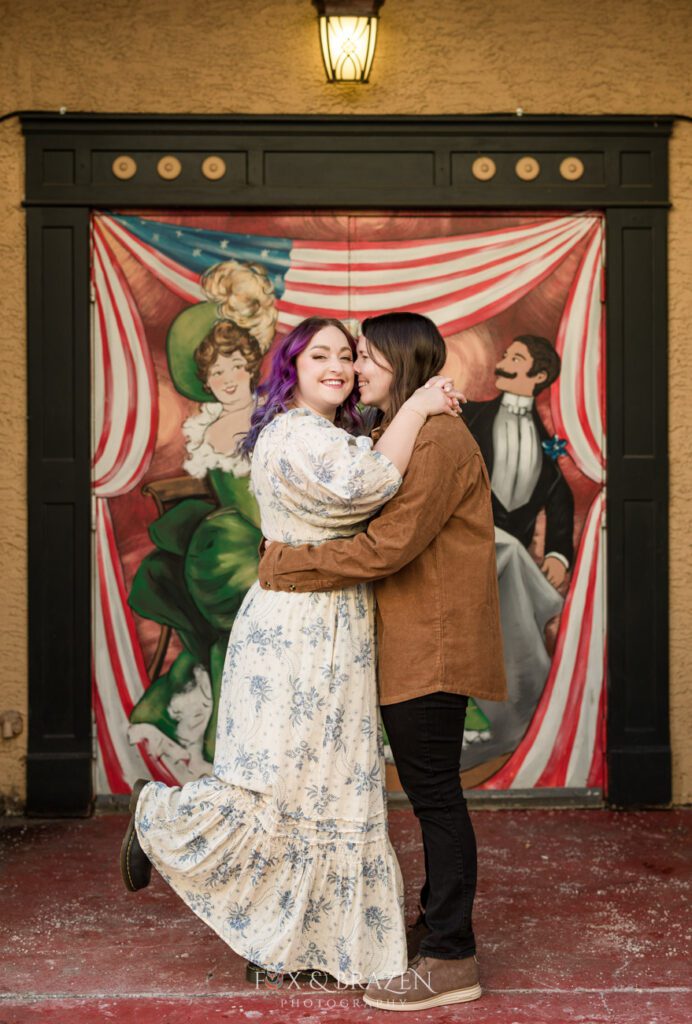 Engaged couple smiling in front of the mural on Bridge Street during their Phoenixville engagement session.