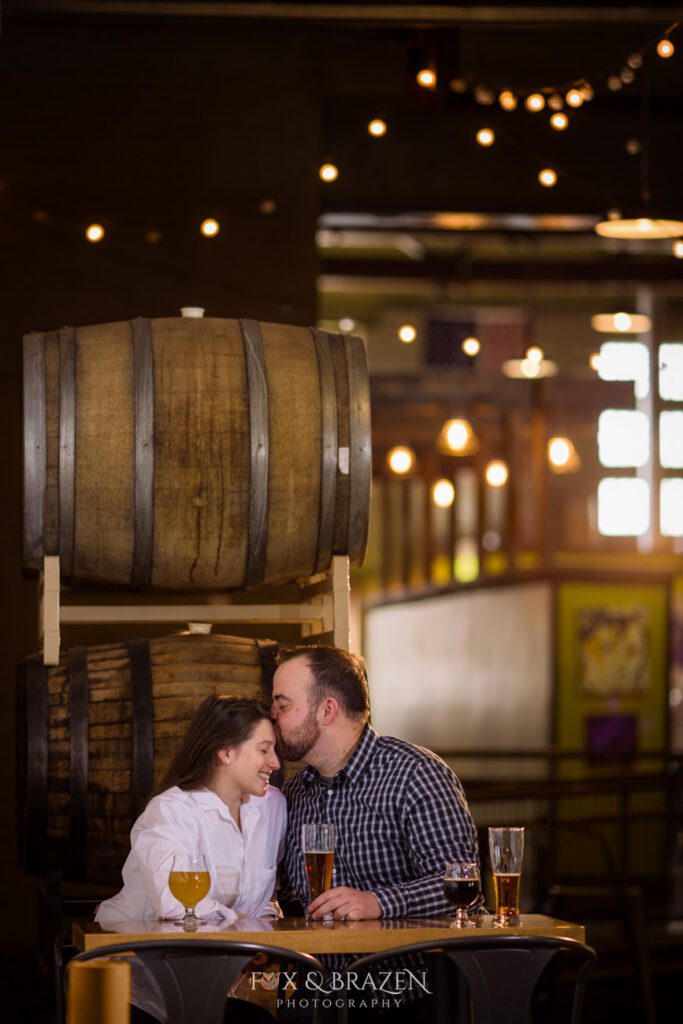 Engaged couple sharing a beer at Root Down Brewing in Phoenixville
