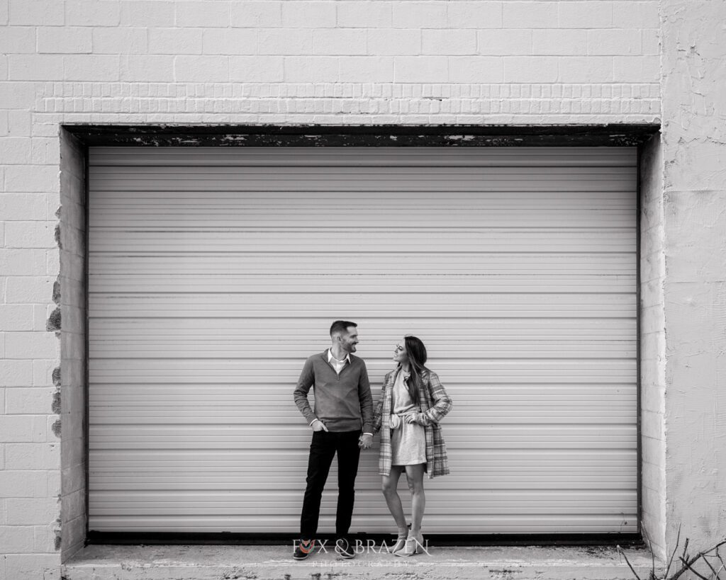 Engaged couple holding hands by metal door in Phoenixville