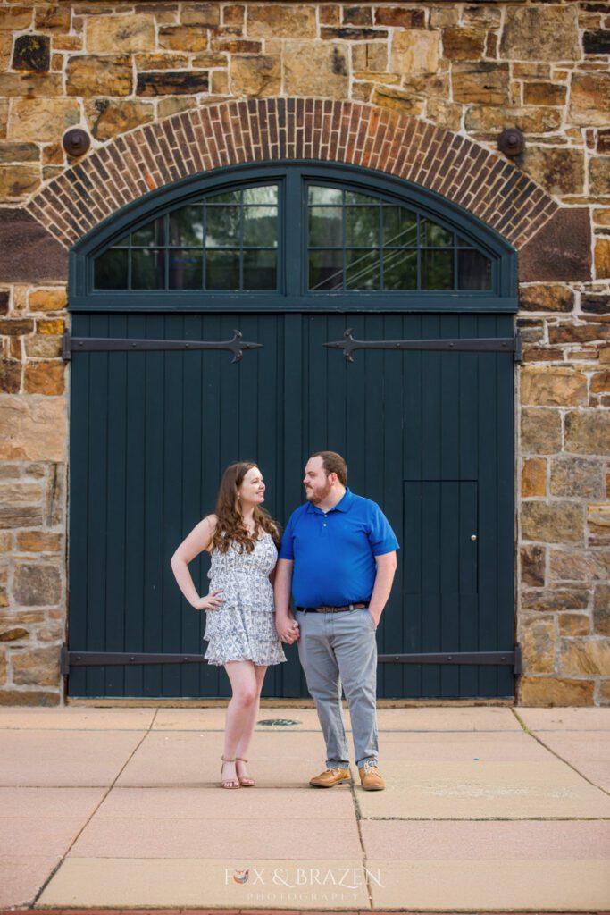 Engaged couple standing in front of Phoenixville Foundry doors