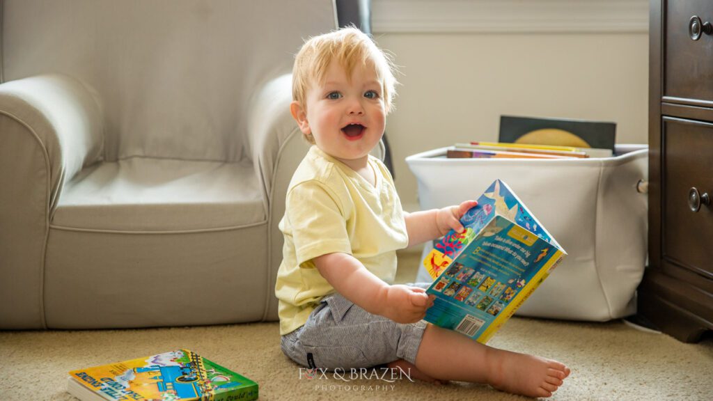 Little boy in yellow shirt sitting on the floor reading books