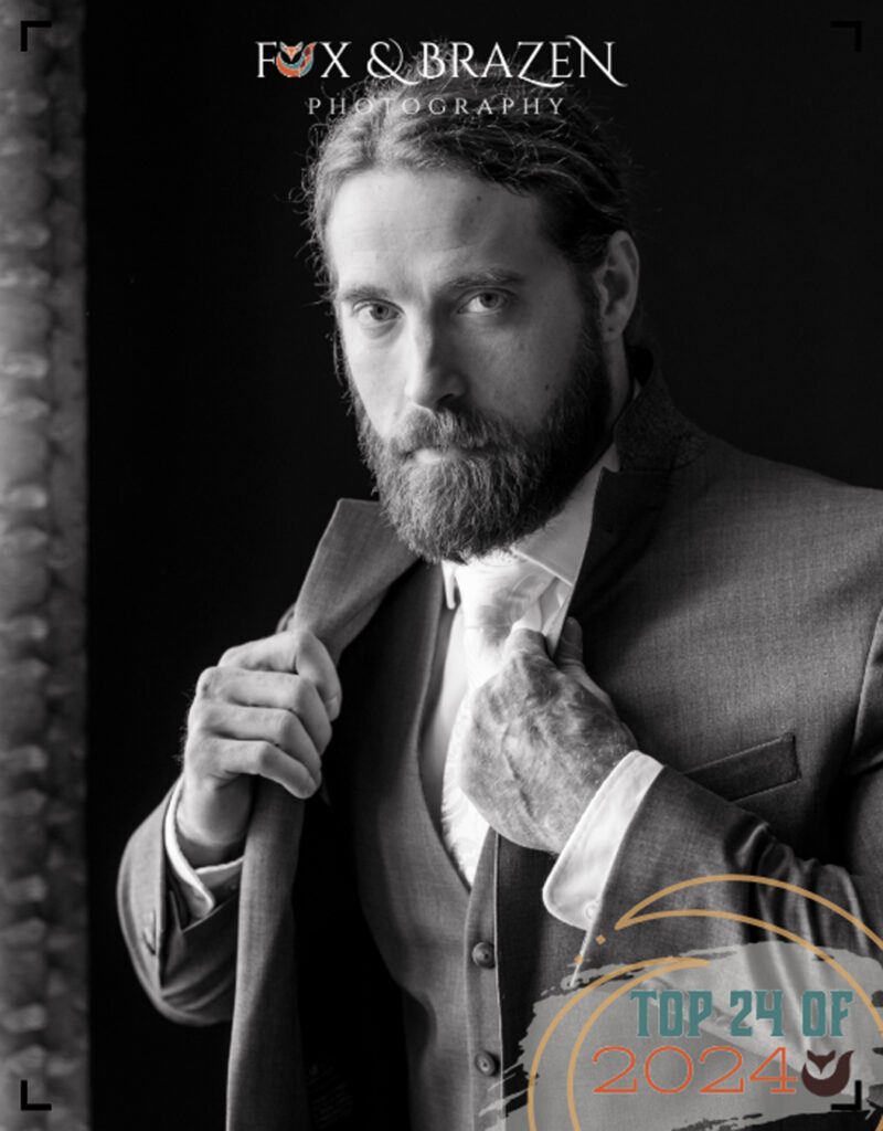 Groom preparing for his wedding with a flipped collar and direct gaze.