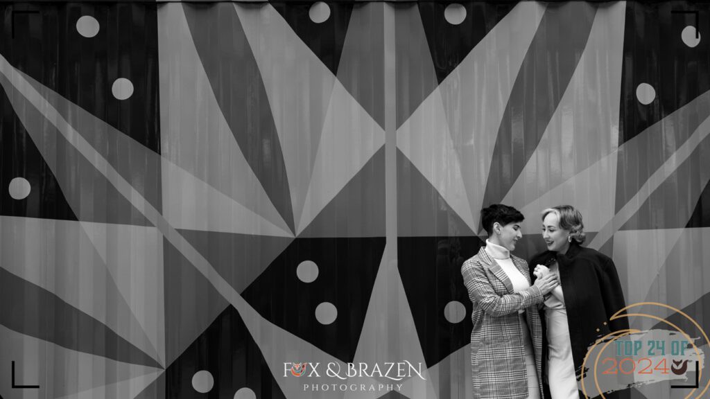 Black-and-white couple’s portrait in front of a textured metal wall at Shutterfest.