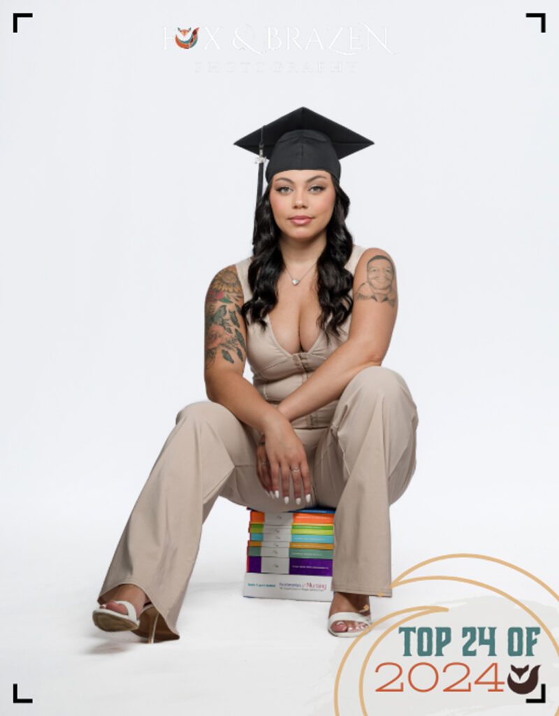 Senior girl sitting on stacked books wearing her graduation cap and tassel as part of the class of 2024.