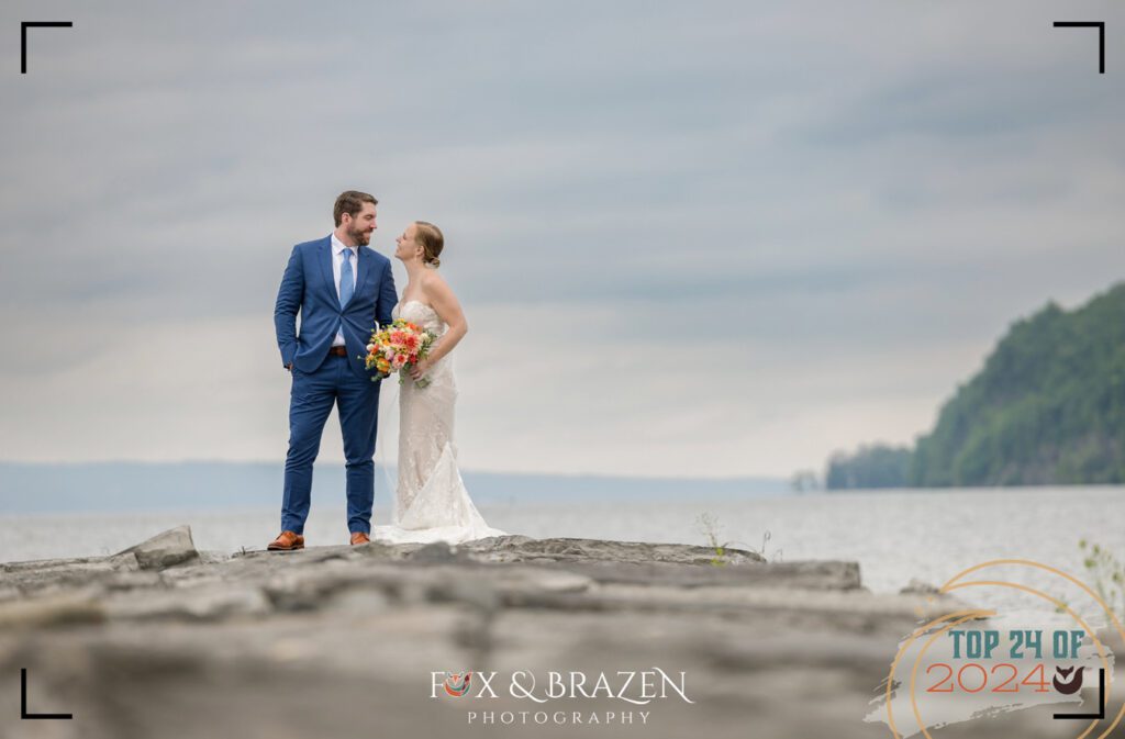 Bride and groom pose on a rock jetty at their Finger Lakes destination wedding in 2024.