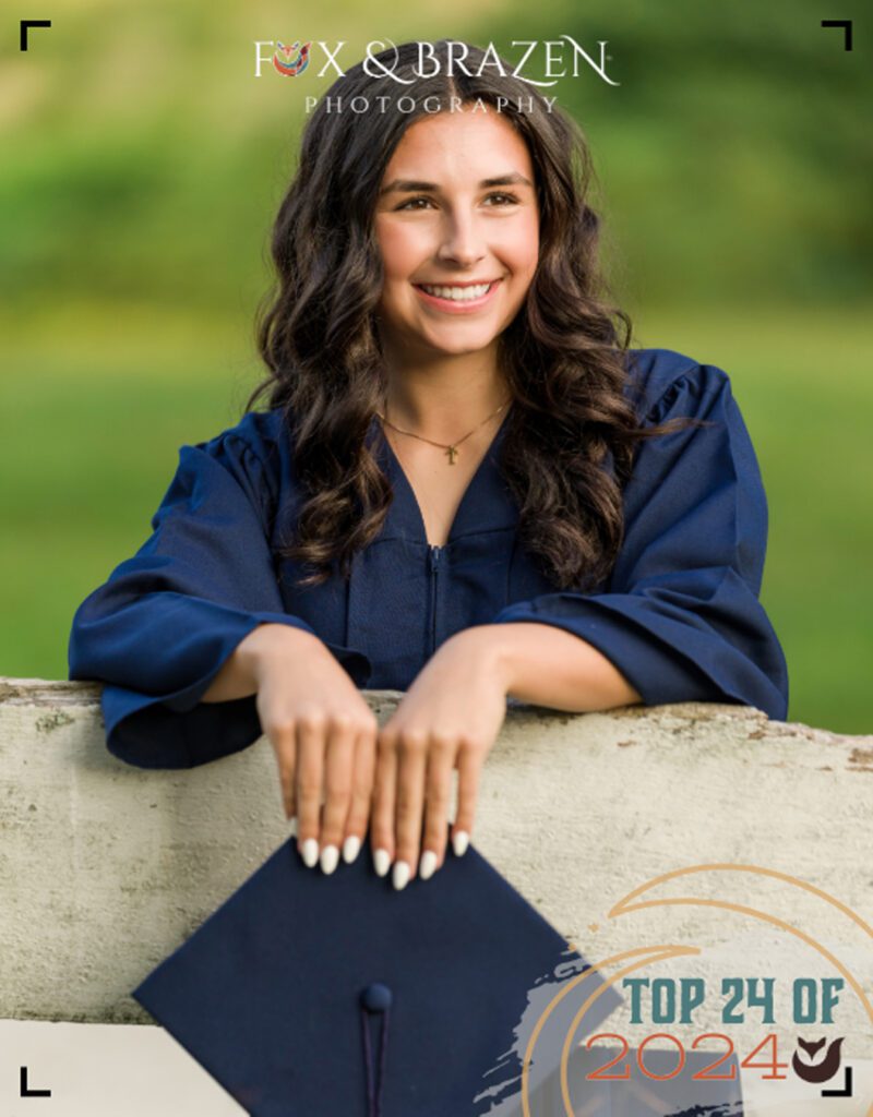 Calm graduating senior posing by a rustic fence in her portrait session.