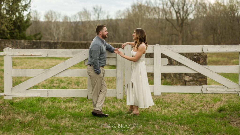 Couple laughing by a white fence at Valley Forge.