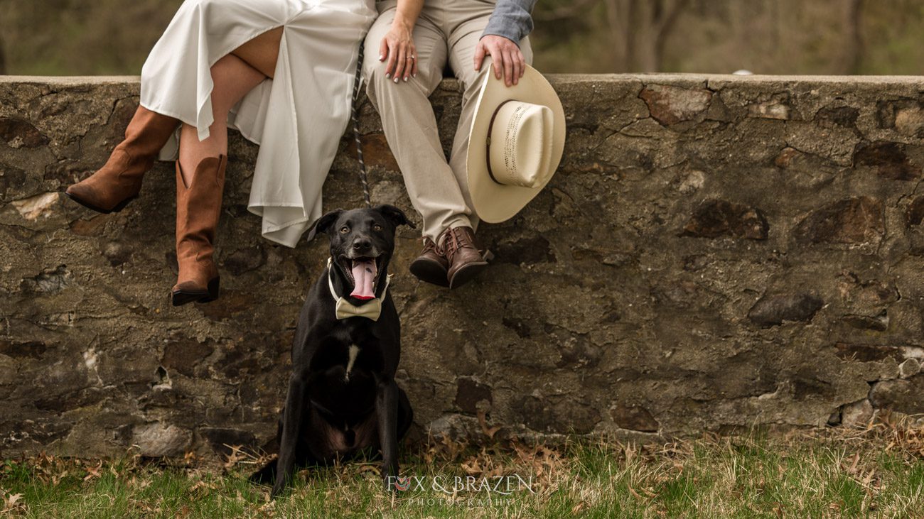 Couple sitting with their black dog during engagement photos.