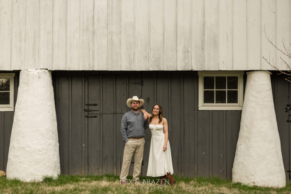 Couple leaning on each other in front of a barn at Valley Forge.
