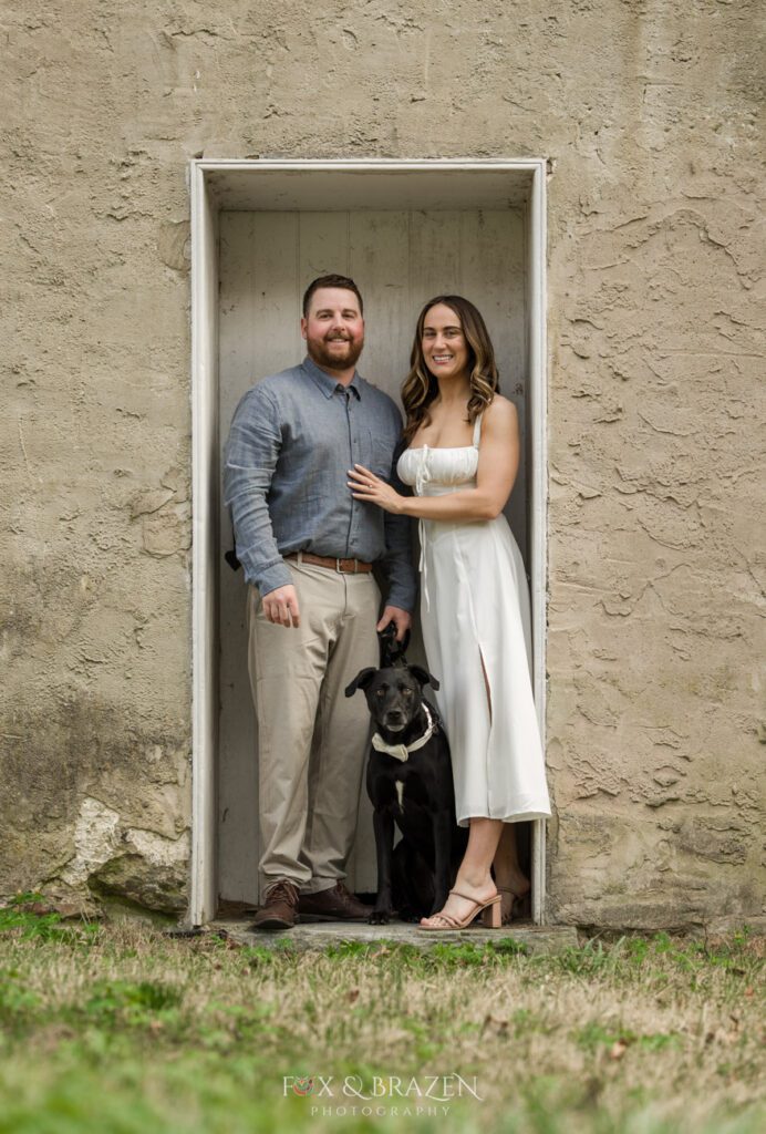 Couple and dog looking at the camera during engagement photos.