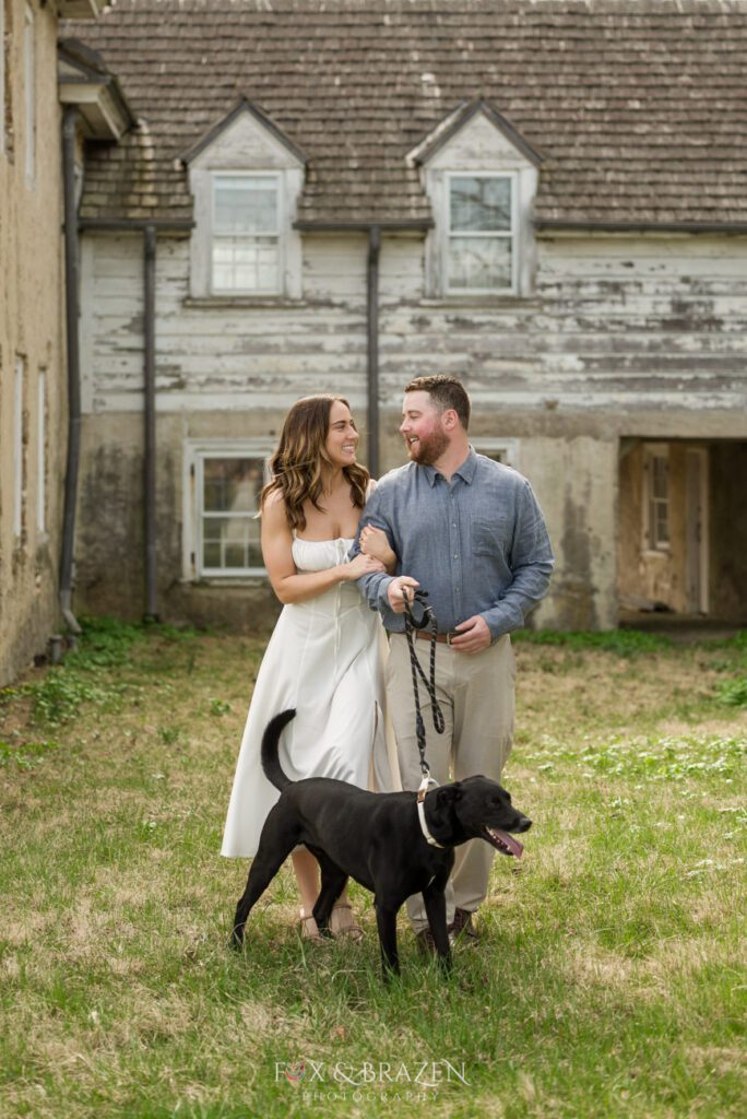 Couple walking with their dog during engagement photos at Valley Forge.