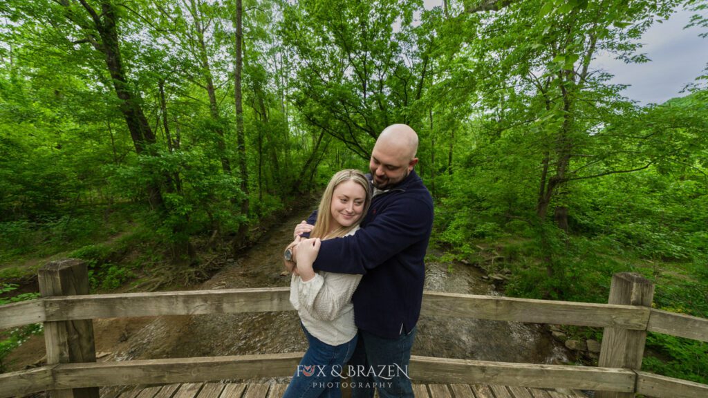 Couple standing on a bridge at Valley Forge, embracing each other.