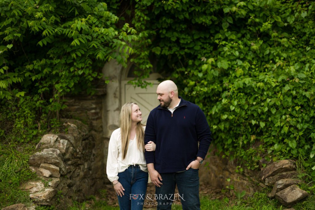 Engaged couple looking at each other lovingly in Valley Forge National Historical Park.