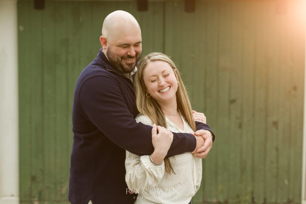 Engaged couple standing in golden light laughing during Valley Forge engagement session.