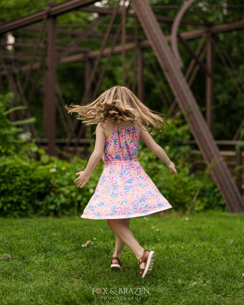 A girl spins in a dance move with hair and dress flared. Her face hidden because privacy matters