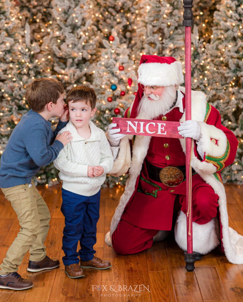 Two siblings telling secrets with Santa Claus.